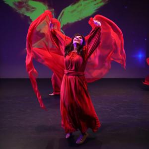 Celeste Varricchio performing in a red dress with a purple background.
