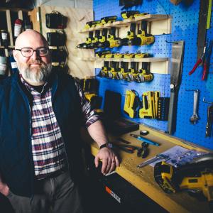 Trevor Flocco standing at his work station with tools in the background