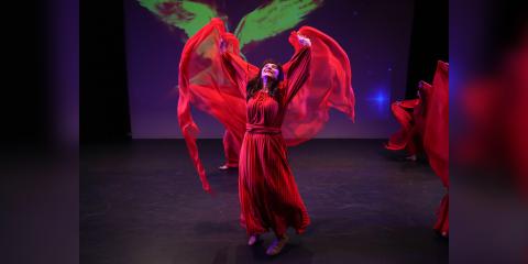 Celeste Varricchio performing in a red dress with a purple background.