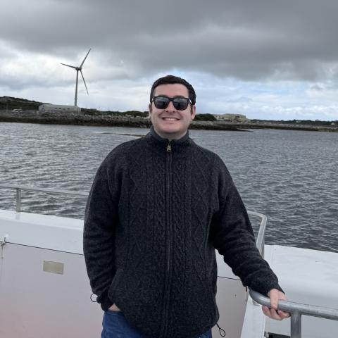 Daniel St. John standing on a boat out on the water on a cloudy day.