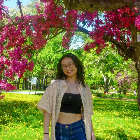Kayla LC standing under a tree with pink flowers on a spring day.