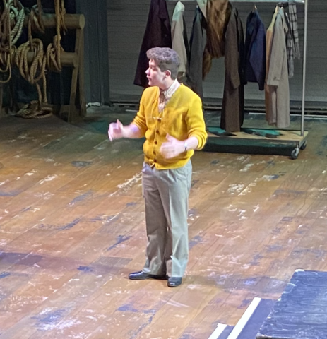 Michael Zaleski wearing a yellow cardigan acting on stage