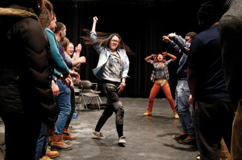Female dancing surrounded by other people cheering her on.
