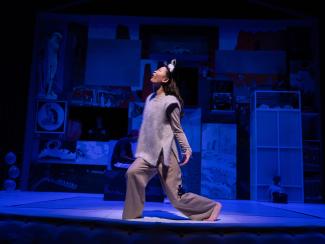 An actress wearing a wolf costume howling at the moon on stage.