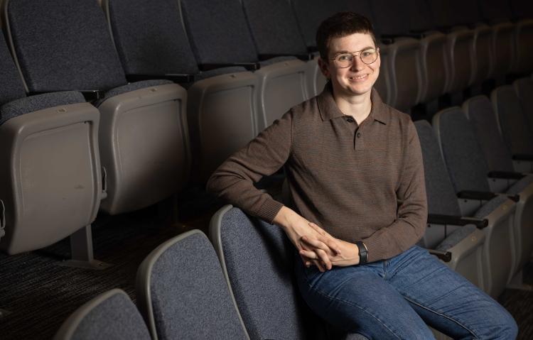 Lyam Gabel sitting in auditorium smiling at the camera