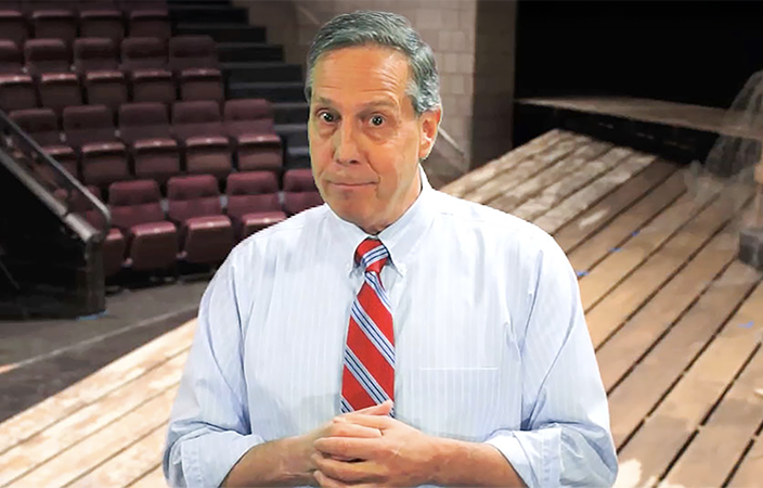Gus Ripa wearing a shirt and tie standing in an auditorium