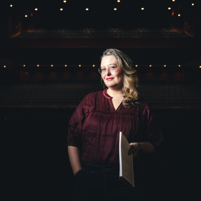 Jessie Dean smiling in an auditorium with a spotlight on her