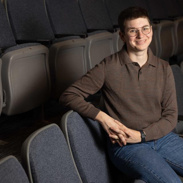 Lyam Gabel sitting in auditorium smiling at the camera