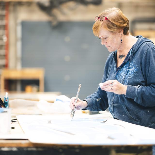 Carrie Ballenger painting in a studio. 