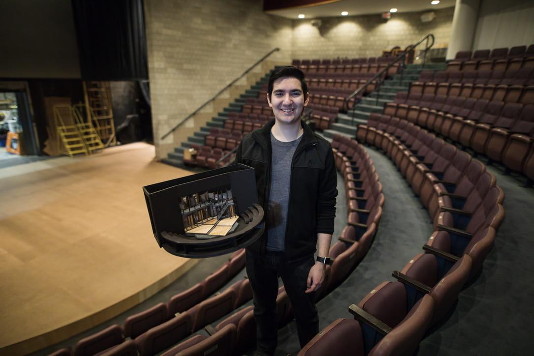Travis Martinez ’21 standing with his design in an auditorium.