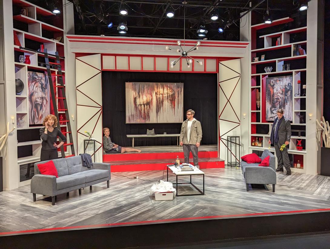 An actress is on the phone while an actor faces her while another actress in the background sitting with her back on the wall.