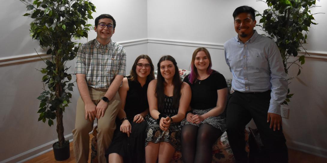 Five Mustard and Cheese members sitting on a couch smiling.